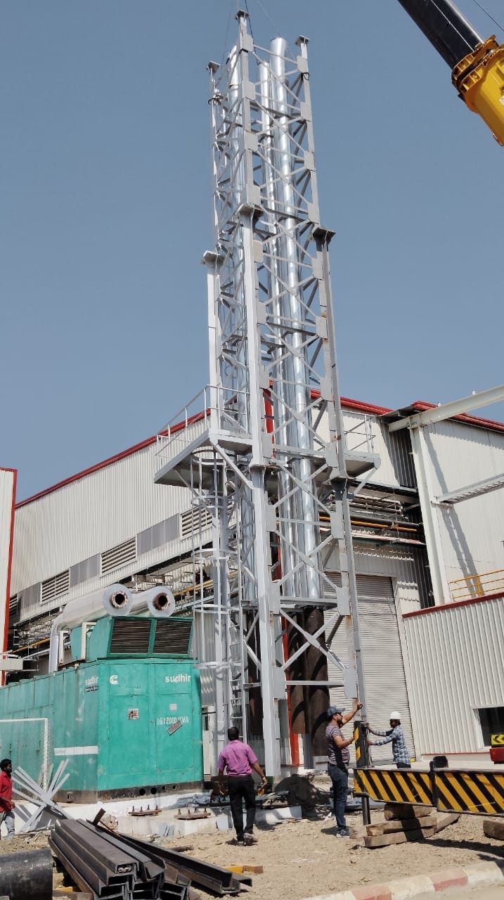 A 30 metre lattice stack being erected by mobile crane beside a DG set at Chakan